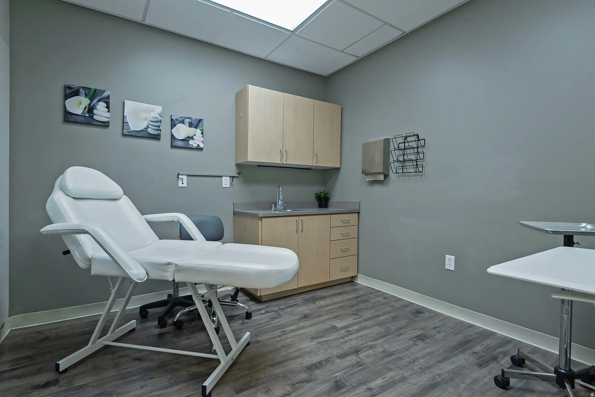 Room featuring wood-finish flooring and a built-in cabinetry unit with an integrated sink and upper cabinets