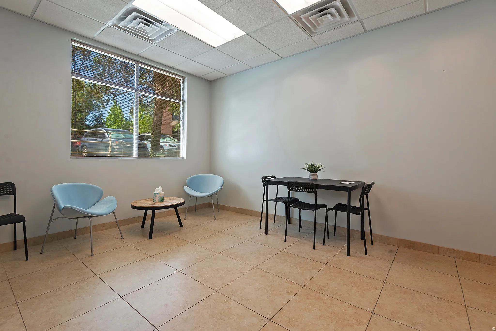 Spacious interior featuring large windows, neutral wall tones, acoustic ceiling tiles, recessed lighting, and durable tile flooring