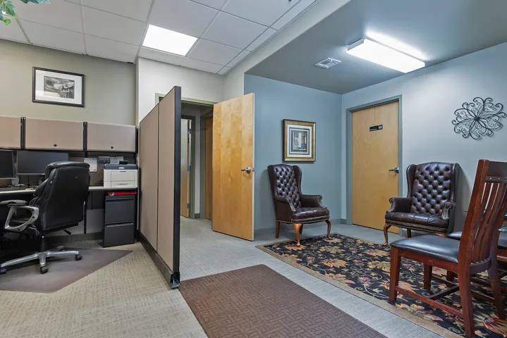 Office space featuring a reception area with tufted leather chairs, wood-finish doors, and recessed ceiling lights