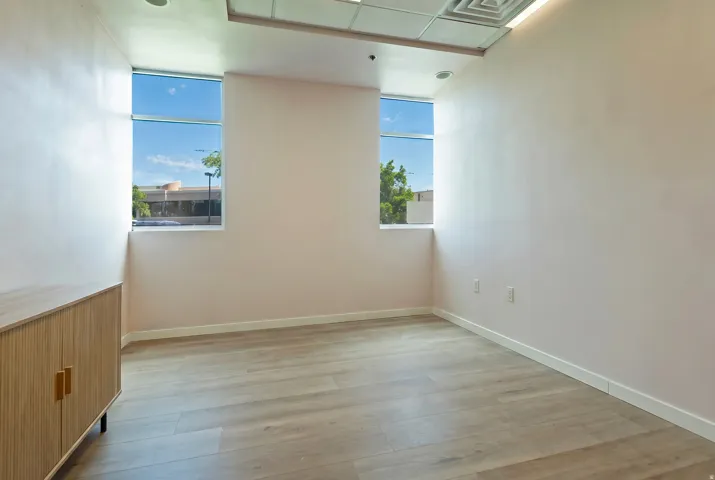 Room featuring two windows, wood-finish flooring, recessed lighting, and a modern built-in cabinet