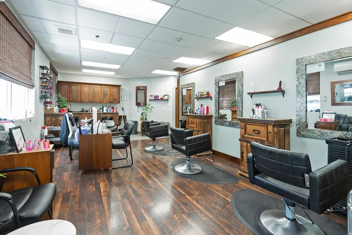 Spacious commercial interior featuring wood-finish flooring, recessed lighting, and multiple workstation areas