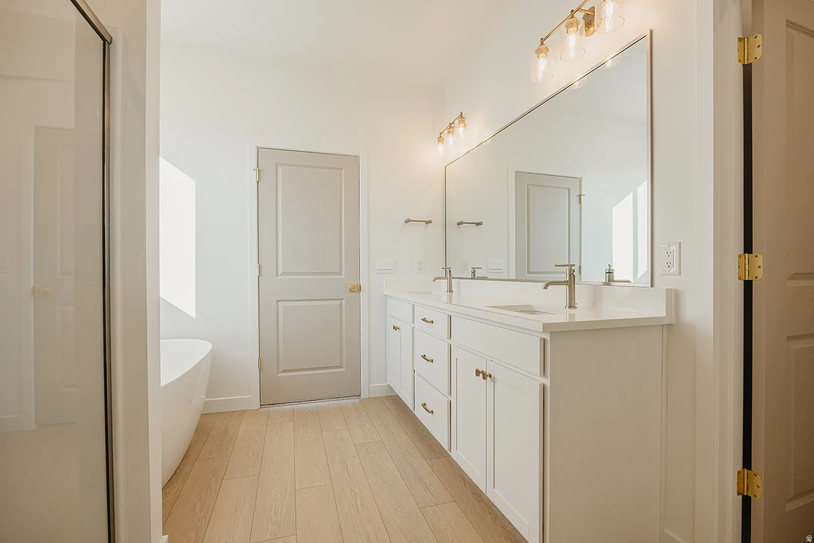 Primary bathroom featuring a dual vanity with white cabinetry, light-toned countertops, and dual wall-mounted light fixtures