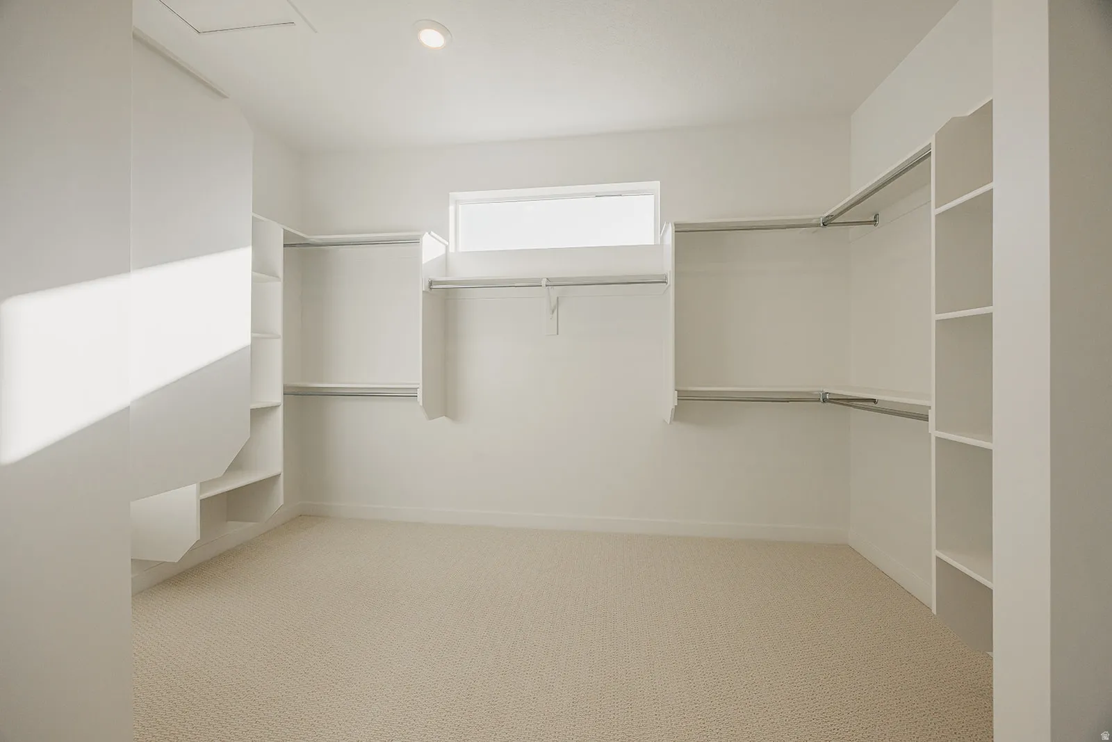 Spacious walk-in closet featuring built-in shelving, multiple hanging rods, recessed ceiling lighting, a high window, and neutral carpeting