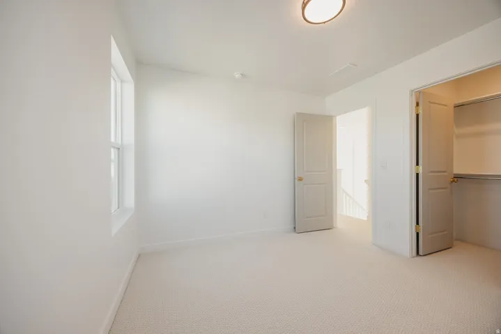 Neutral-toned carpet flooring in a room featuring white walls, a single pane window, and a flush mount ceiling light