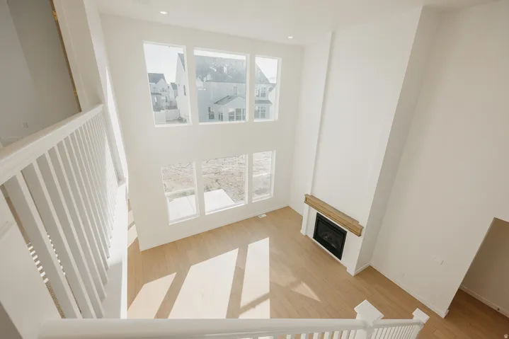 Two-story living area featuring extensive window array, light wood-finish flooring, and a fireplace with a wood mantel