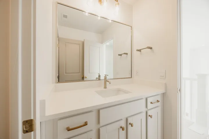 Modern bathroom vanity featuring a rectangular undermount sink, light-toned countertop, and gold-finish hardware