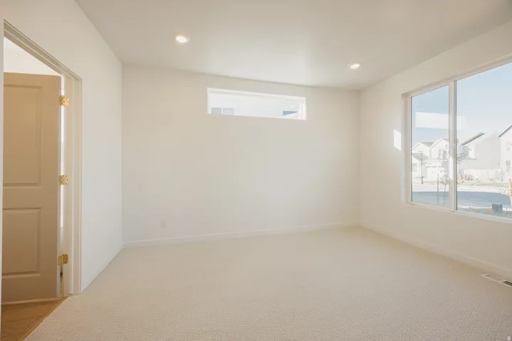 Primary bedroom featuring light-colored carpeting, white walls, and recessed lighting
