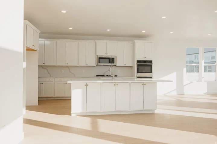 Modern kitchen featuring white cabinetry, a spacious island with sink, stainless steel appliances, recessed lighting, and wood-finish flooring
