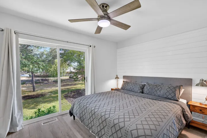 Spacious room with wood-finish flooring, a contemporary ceiling fan, and a shiplap accent wall