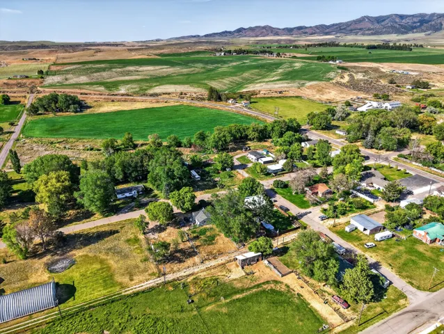 Expansive aerial perspective showcasing a rural community with surrounding agricultural fields and distant mountains