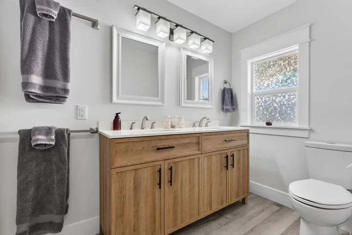 Dual vanity with a wood-finish cabinet, white countertop, and brushed nickel faucets
