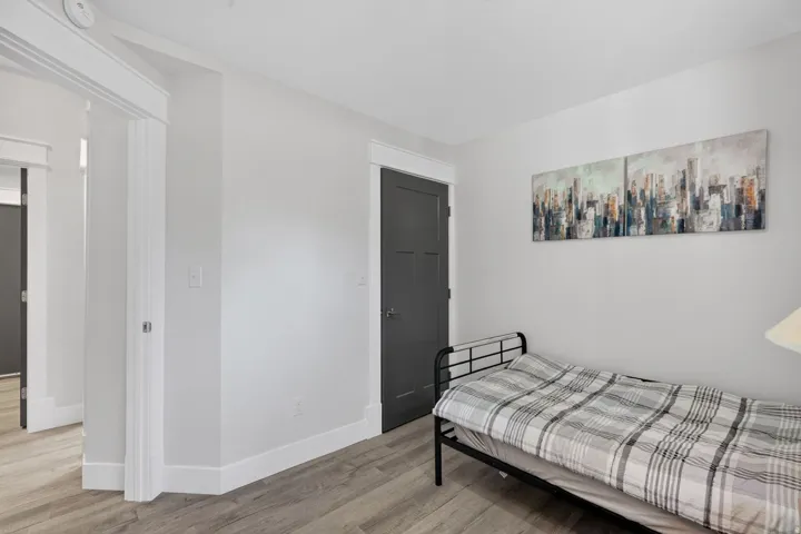 Interior room featuring wood-finish flooring and a dark panel door with white trim