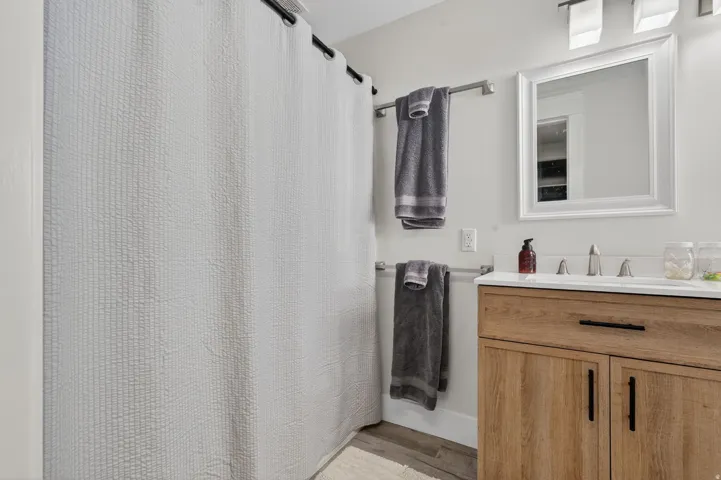 Bathroom featuring a wood-finish vanity with black hardware, a white countertop, and a rectangular undermount sink