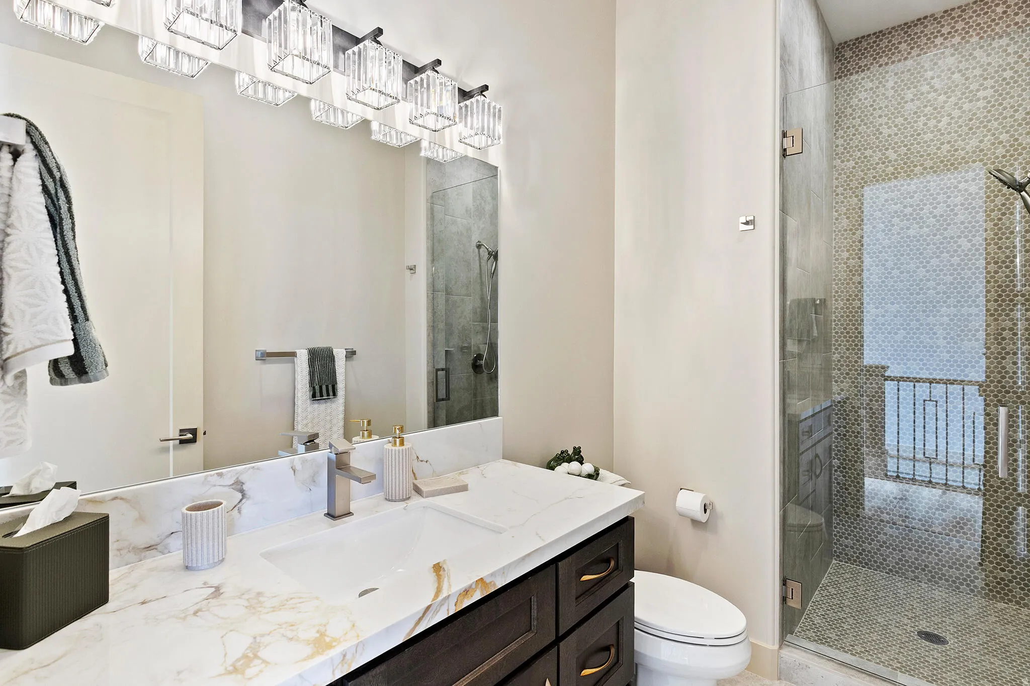 Bathroom featuring a dark wood-finish vanity with a white and gold veined countertop, an undermount sink, and a brushed nickel faucet