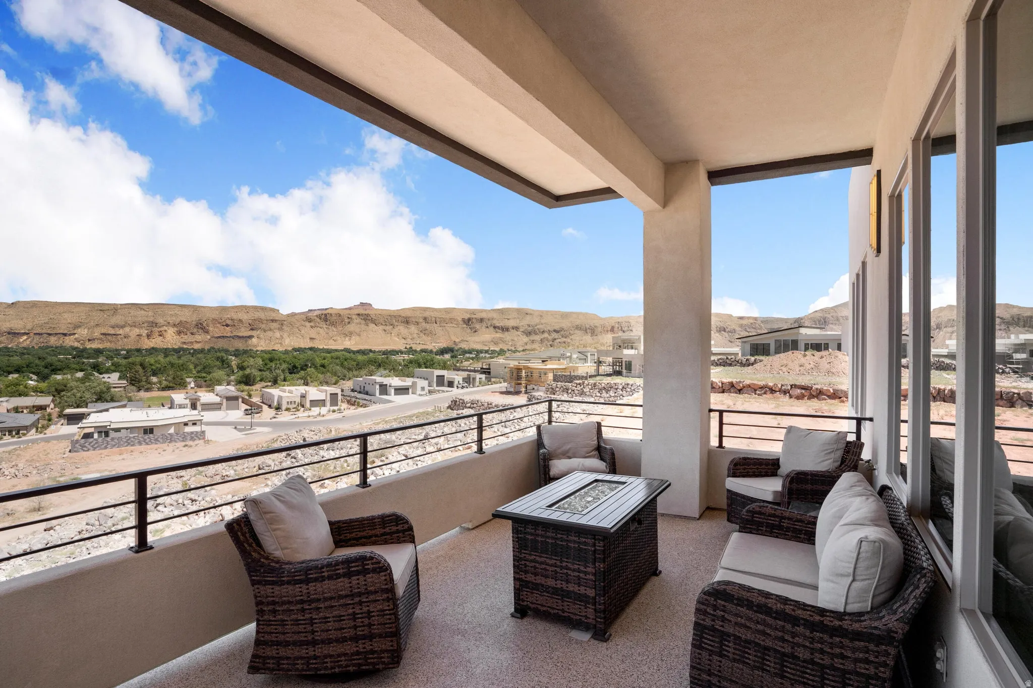 Spacious outdoor balcony featuring a textured concrete floor, a metal railing, and a stucco exterior