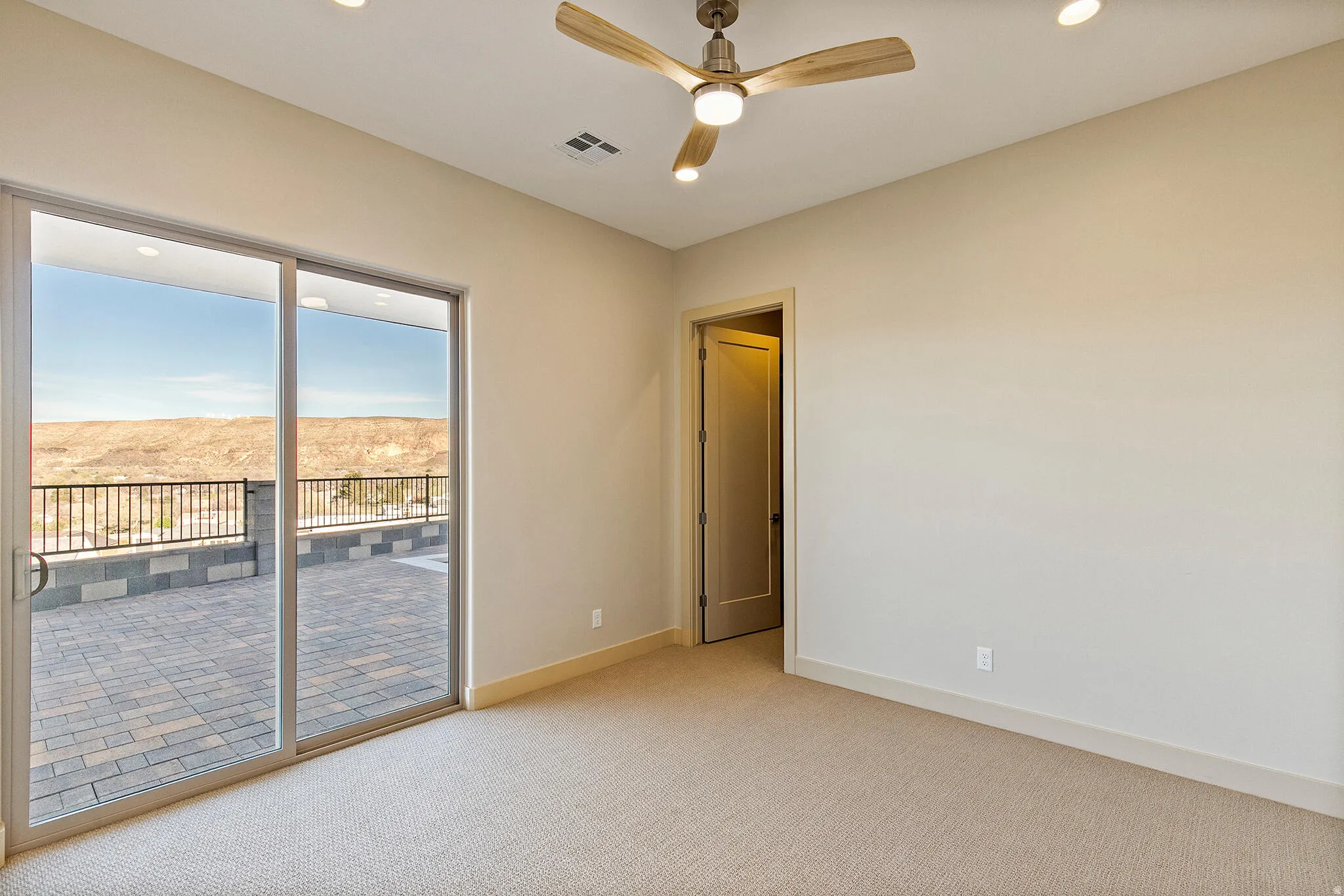 Spacious interior with neutral-toned walls, recessed lighting, and a ceiling fan with light wood-finish blades