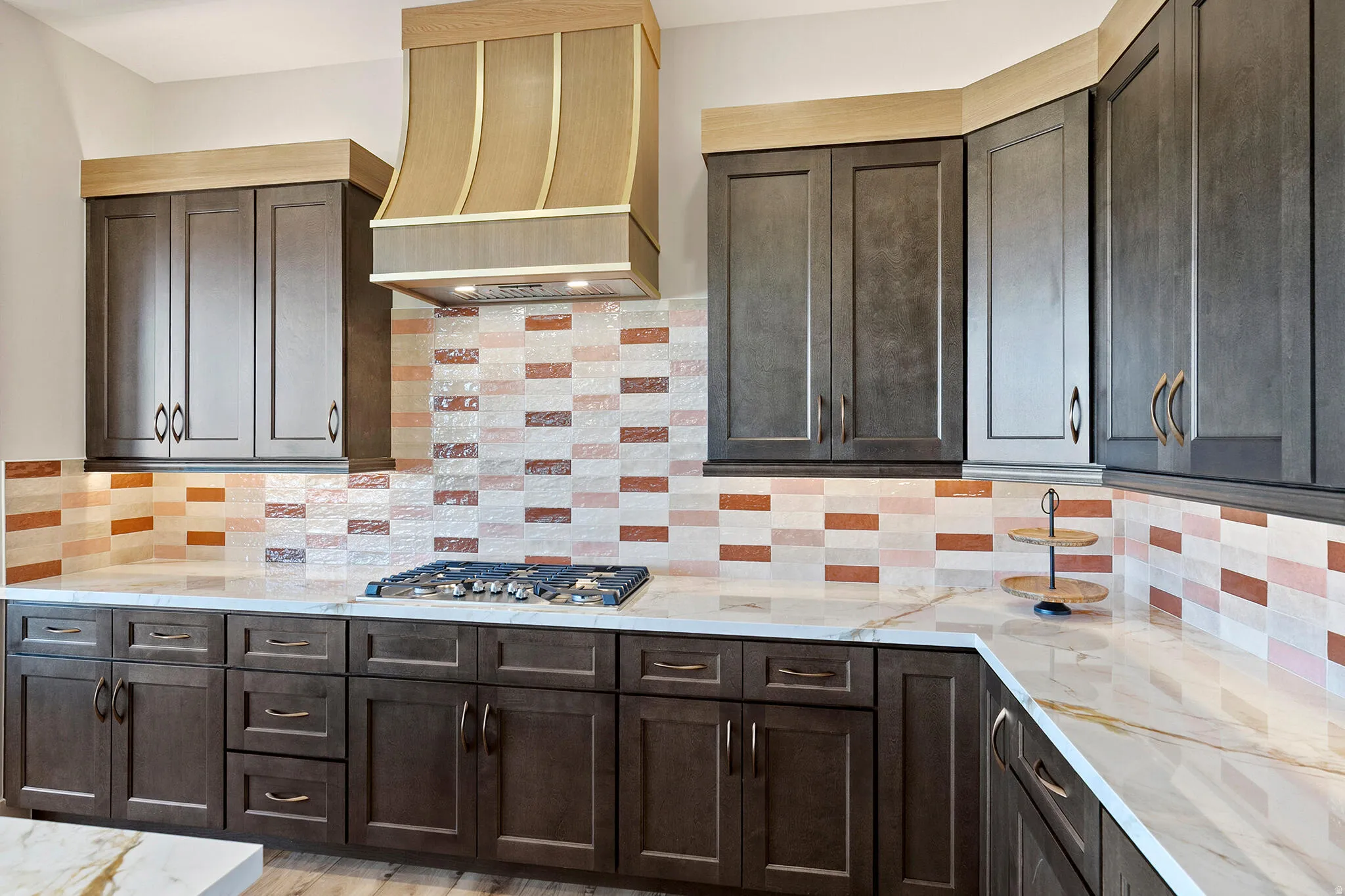 Kitchen featuring dark wood-finish cabinetry, light-toned countertops with veining, and a gas range