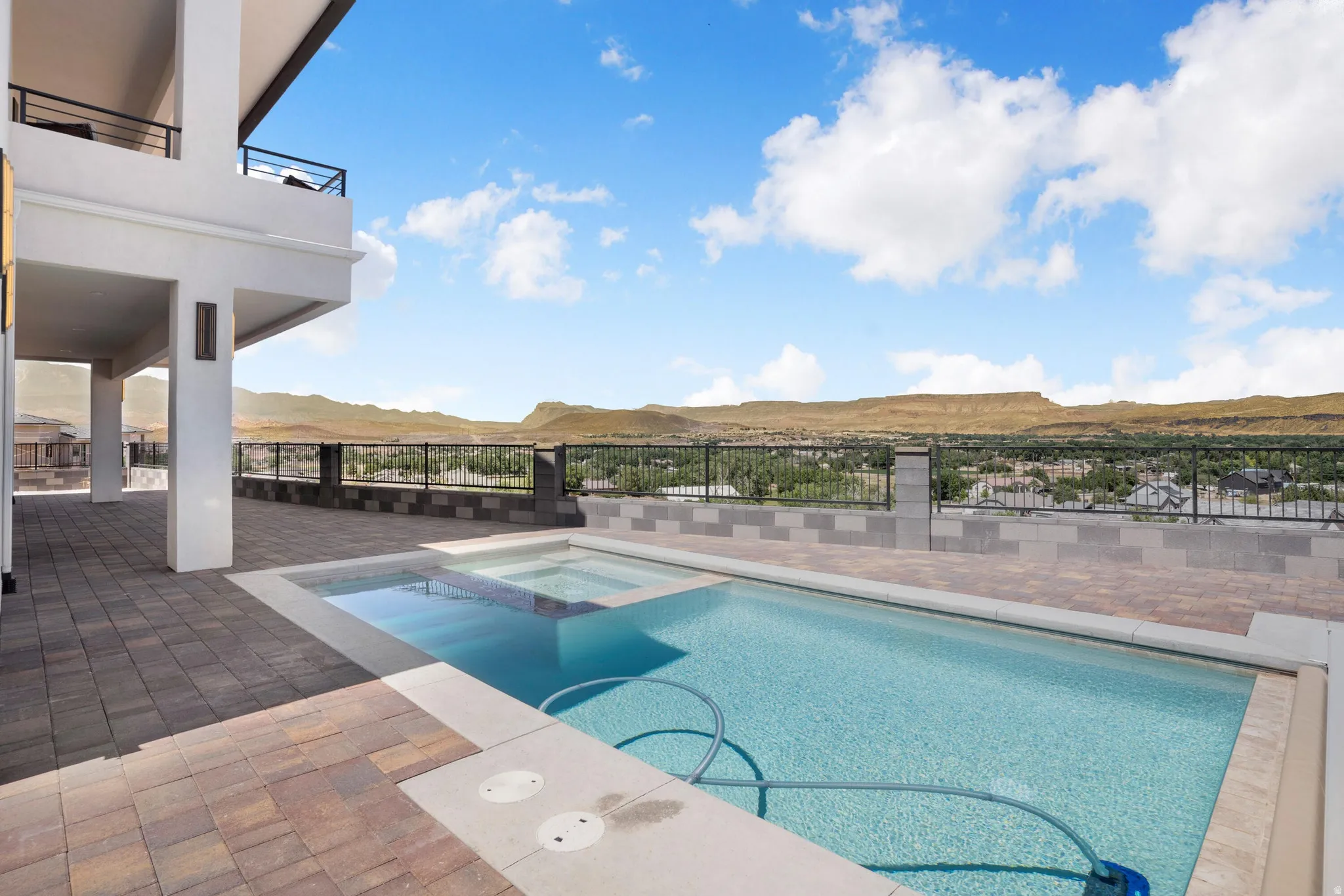 Outdoor pool and spa with a paver patio and expansive mountain scenery