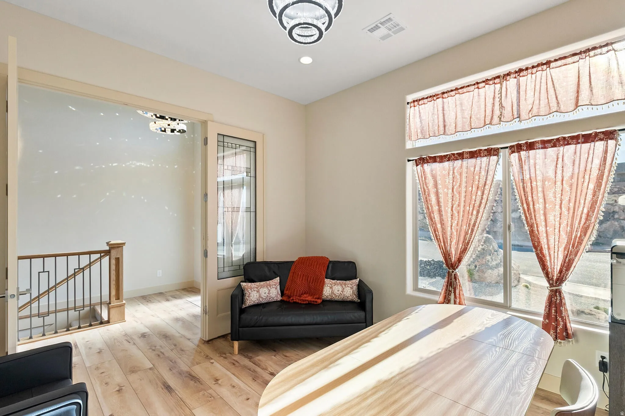 Room with light wood-finish flooring and a contemporary chandelier