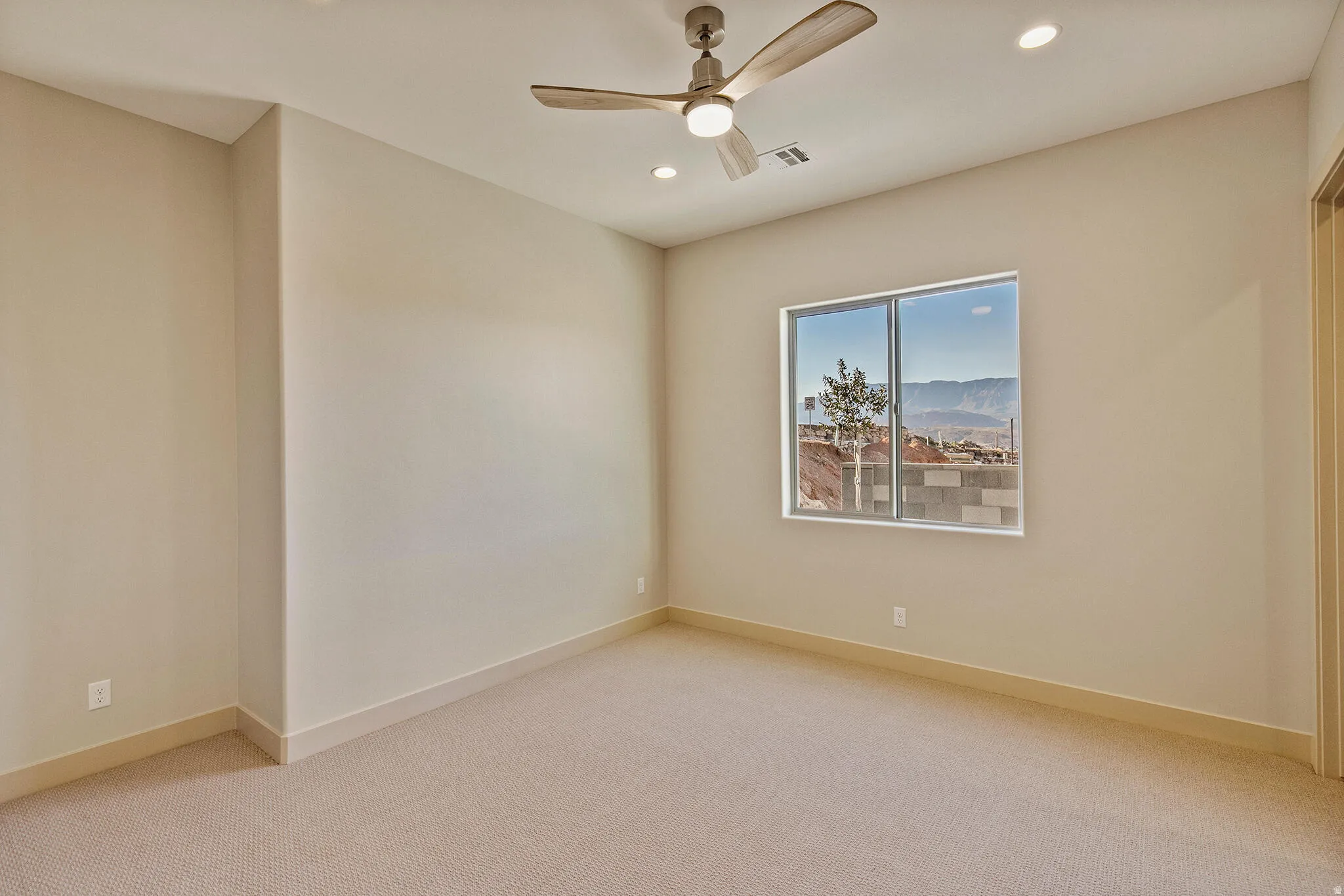 Carpeted room featuring a ceiling fan with integrated lighting, recessed ceiling lights, a large window, and beige wall paint
