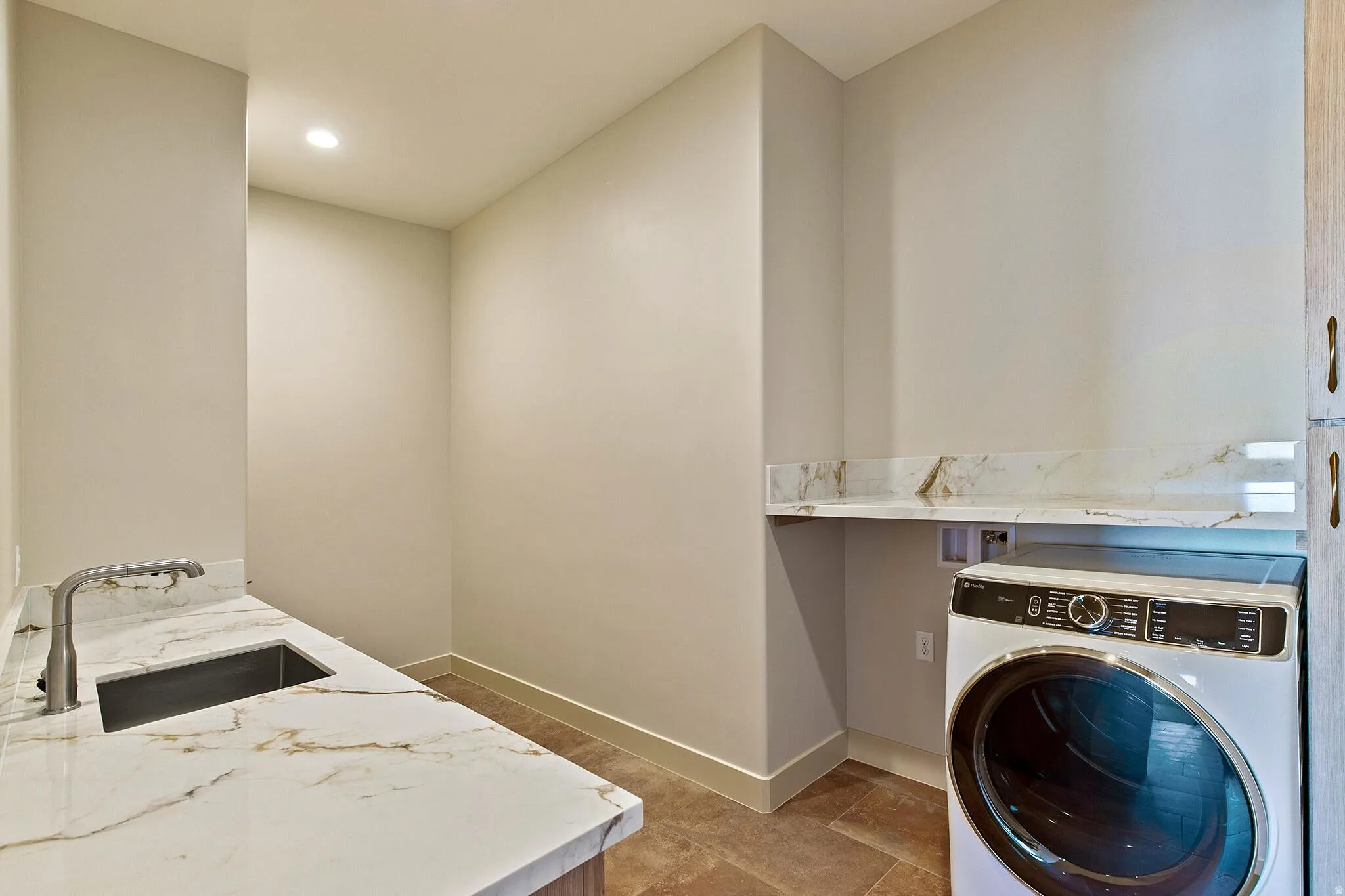 Laundry area featuring a utility sink with a brushed nickel faucet, stone-finish countertops, and a full-size front-load washer