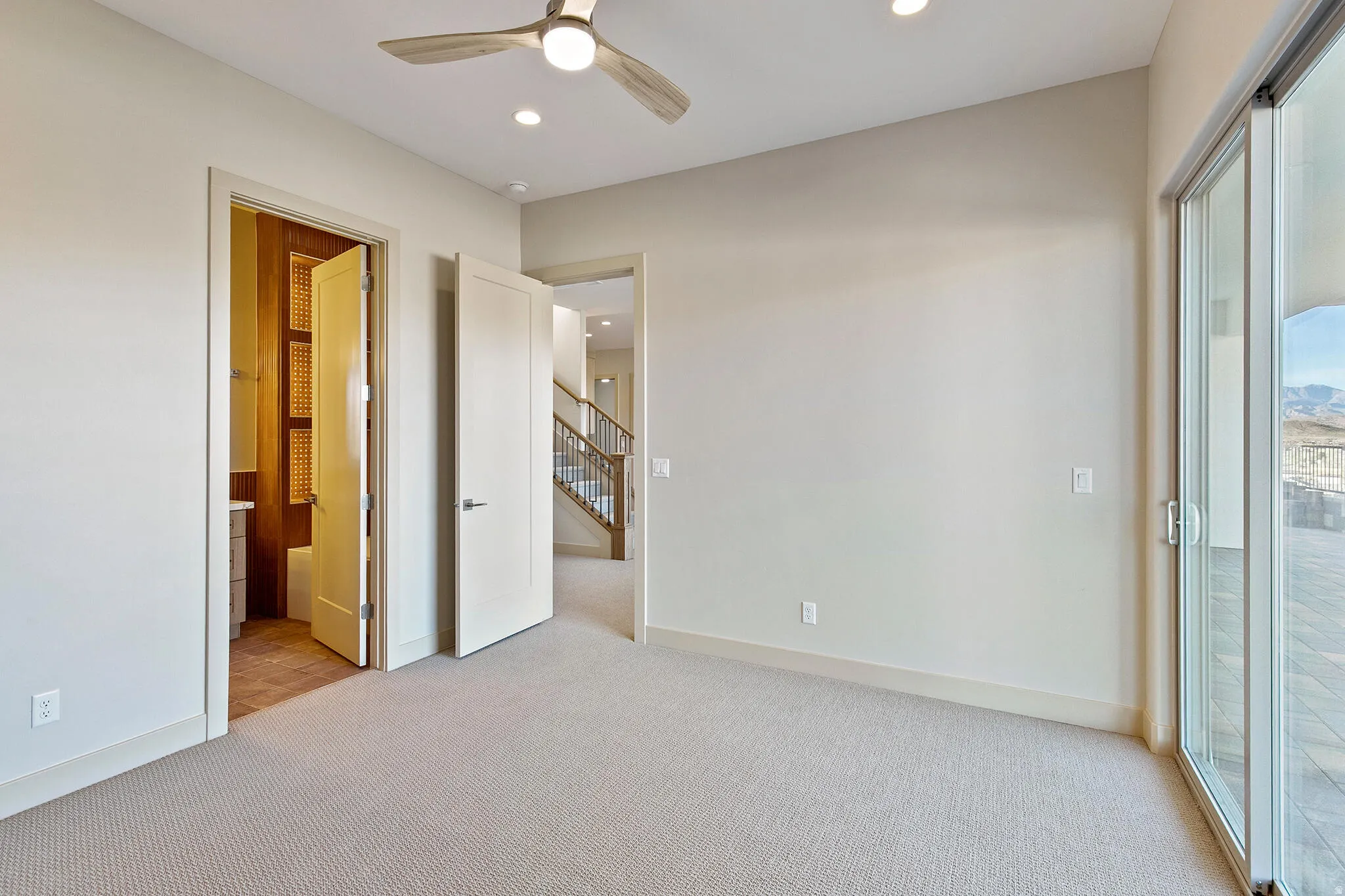Carpeted room with a ceiling fan, recessed lighting, and a sliding glass door providing access to an outdoor patio