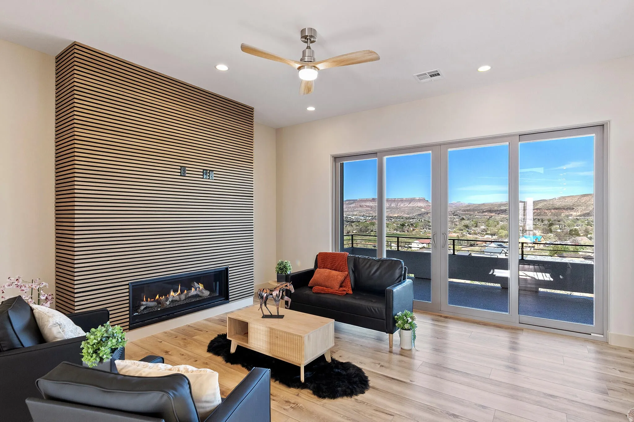 Spacious living area featuring a linear gas fireplace set into a slatted wood accent wall, wood-finish flooring, and recessed lighting
