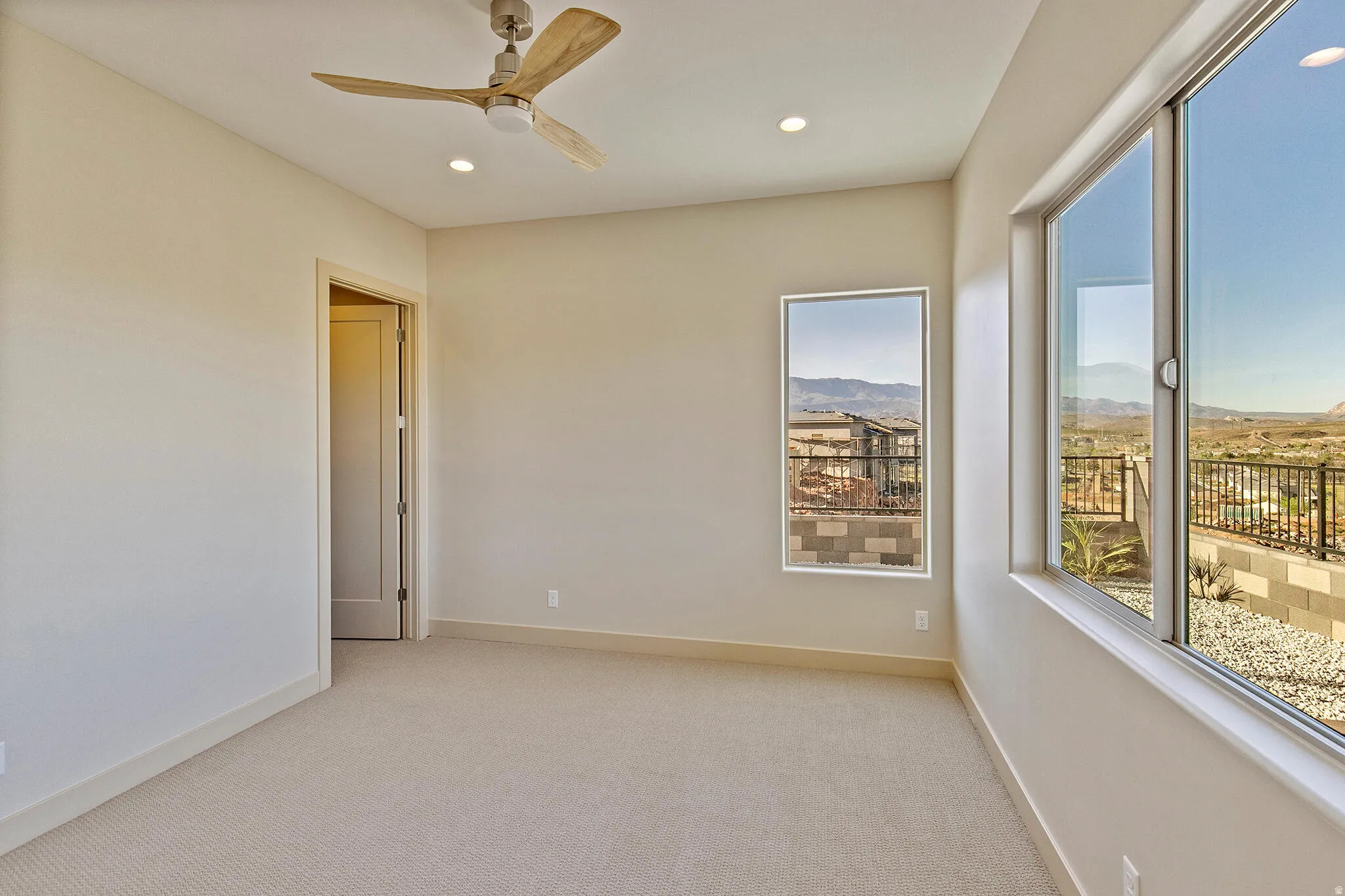Carpeted room featuring a ceiling fan, recessed lighting, and multiple windows