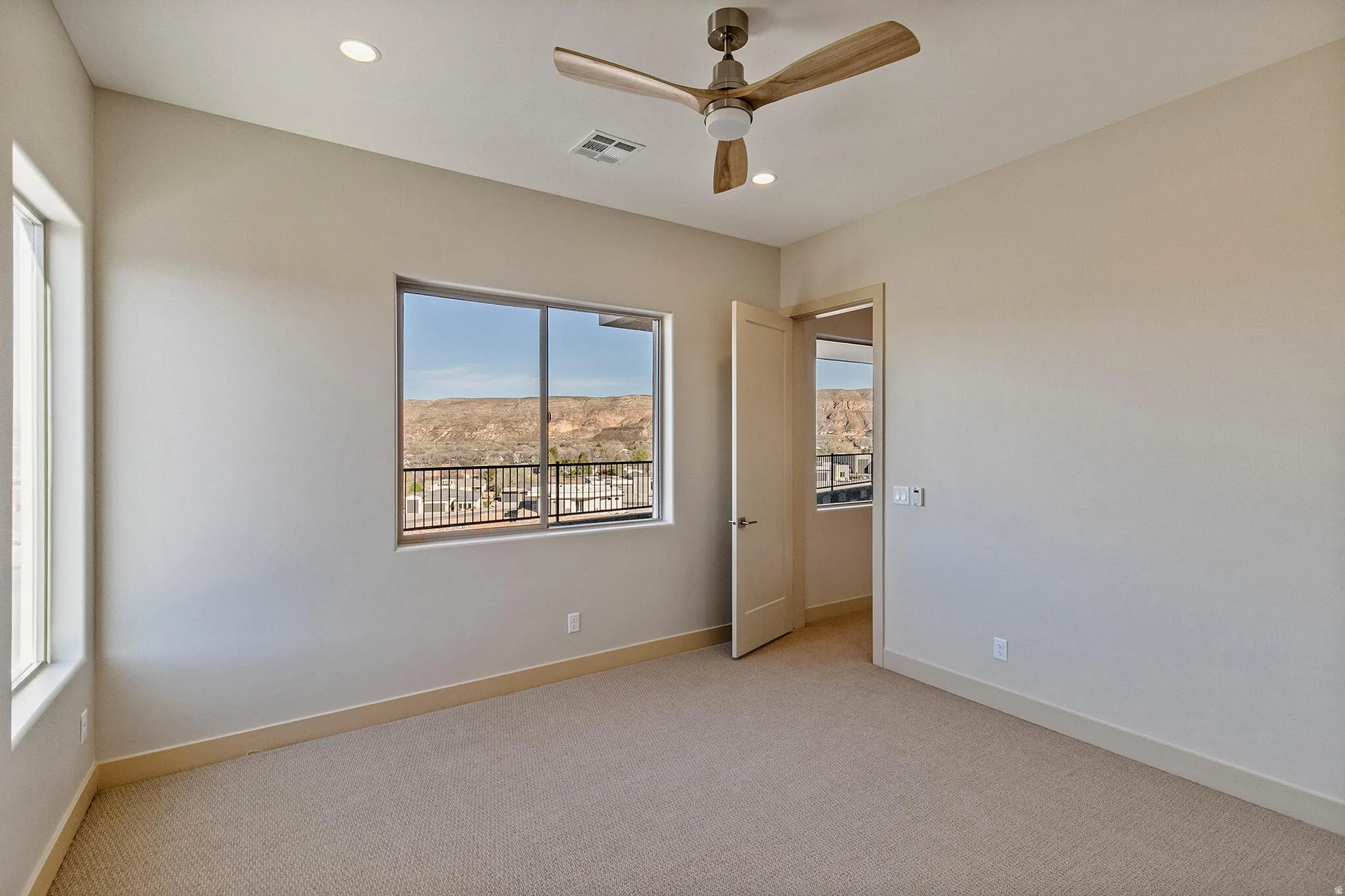 Carpeted room featuring a ceiling fan with light, recessed lighting, and expansive windows showcasing a mountain backdrop