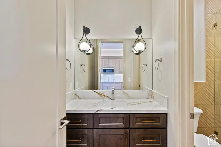 Bathroom vanity with a white countertop featuring gold-toned veining, dark wood-finish cabinetry, and gold-tone hardware