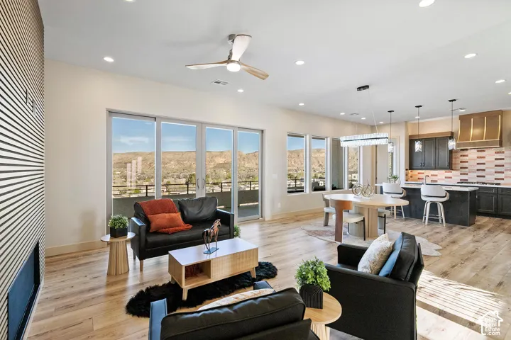 Open-concept living space featuring wood-finish flooring, a linear fireplace with a textured accent wall, and a ceiling fan