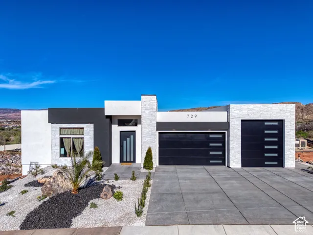 Modern exterior featuring a prominent black and white facade, stacked stone accents, a dark entry door with vertical glass inserts, and two black garage doors with horizontal window panels