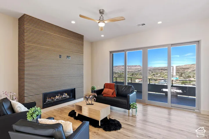 Spacious living area featuring a linear gas fireplace set into a slatted wood accent wall, wood-finish flooring, and recessed lighting