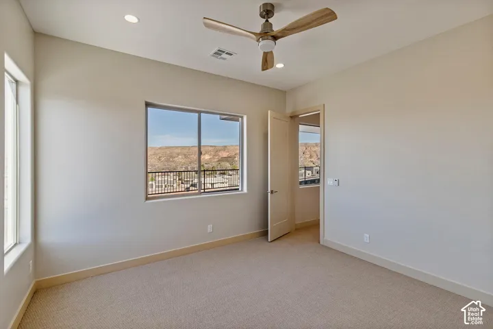 Carpeted room featuring a ceiling fan with light, recessed lighting, and expansive windows showcasing a mountain backdrop