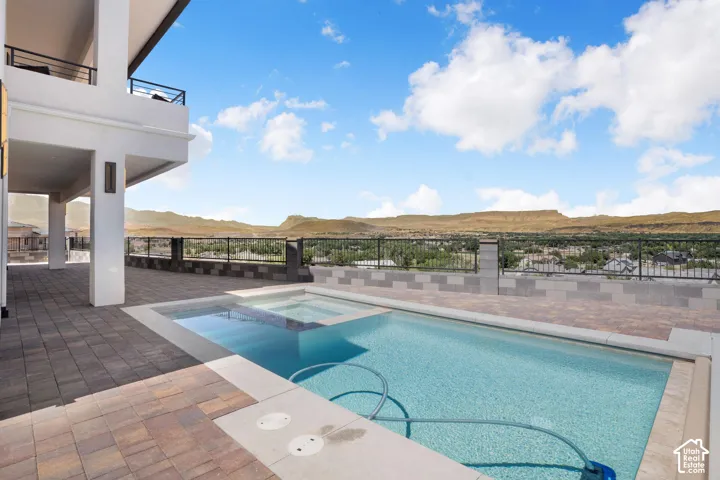 Outdoor pool and spa with a paver patio and expansive mountain scenery