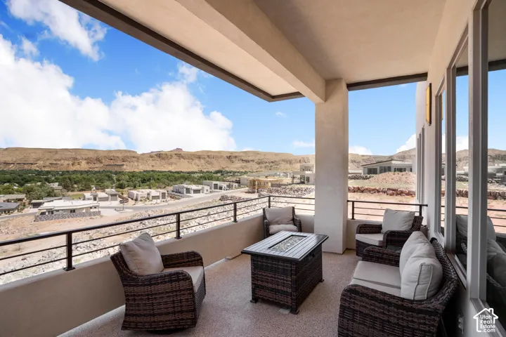 Spacious outdoor balcony featuring a textured concrete floor, a metal railing, and a stucco exterior