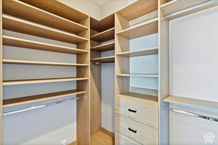 Custom closet system featuring wood-finish shelving, built-in drawers with dark hardware, and chrome hanging rods