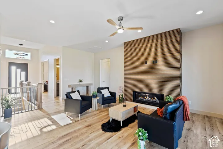 Spacious living area featuring a contemporary linear fireplace with a slatted wood accent wall, wood-finish flooring, recessed lighting, and a ceiling fan