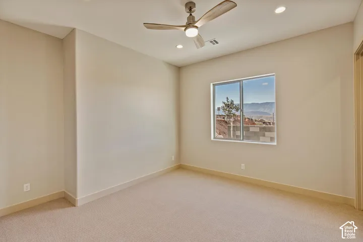 Carpeted room featuring a ceiling fan with integrated lighting, recessed ceiling lights, a large window, and beige wall paint