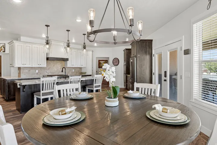 Open-concept dining area featuring a circular wood-finish table and a five-light chandelier