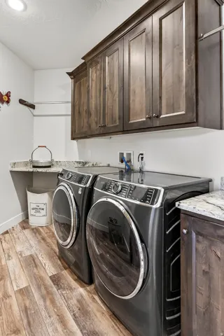 Laundry area featuring wood-finish flooring and upper wood cabinetry