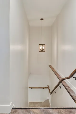 Stairwell with wood-finish flooring at the landing and a contemporary pendant light fixture