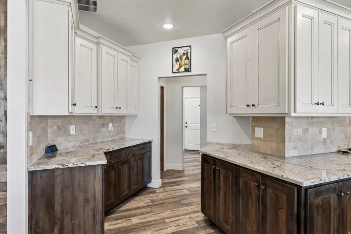 Kitchen featuring two-tone cabinetry with white upper cabinets and dark wood-finish lower cabinets