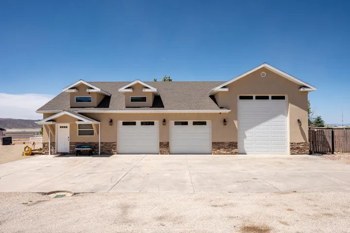 Exterior featuring a three-car garage, stucco siding, and stone accents