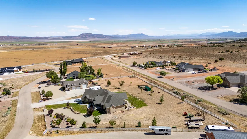 Expansive property featuring a paved driveway, a manicured lawn area, and established landscaping, surrounded by open terrain and distant mountains