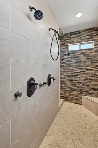 Walk-in shower featuring dual shower heads, dark bronze fixtures, and a horizontal rectangular window