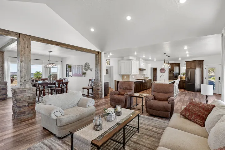 Spacious open-concept living area featuring wood-finish flooring, vaulted ceilings, and recessed lighting