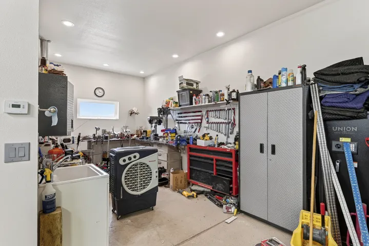 Utility space featuring a single window, recessed ceiling lighting, a utility sink, and wall-mounted shelving