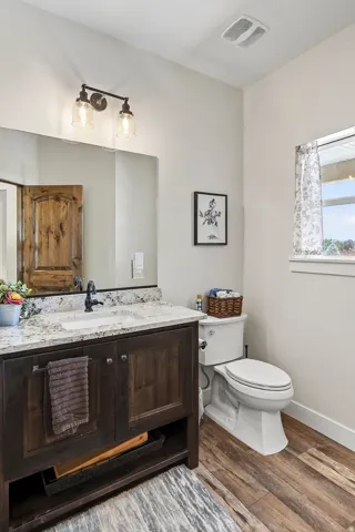 Bathroom featuring a dark wood-finish vanity with a granite countertop, undermount sink, and black faucet