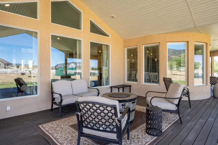 Spacious covered patio featuring composite decking and a stucco exterior with large windows